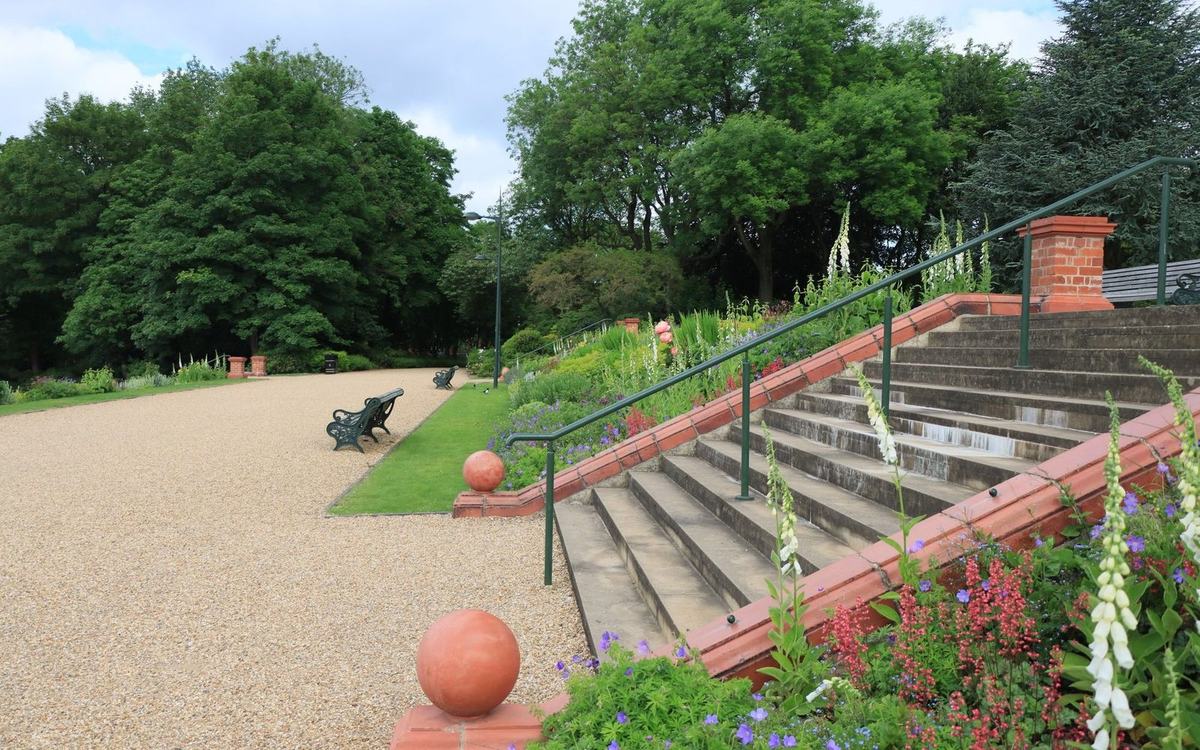 Stone garden steps with a handrail beside planted borders